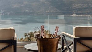 Une vue sur un lac avec des montagnes en arrière-plan, une bouteille de champagne dans un seau en métal et deux chaises placées face à ce paysage.