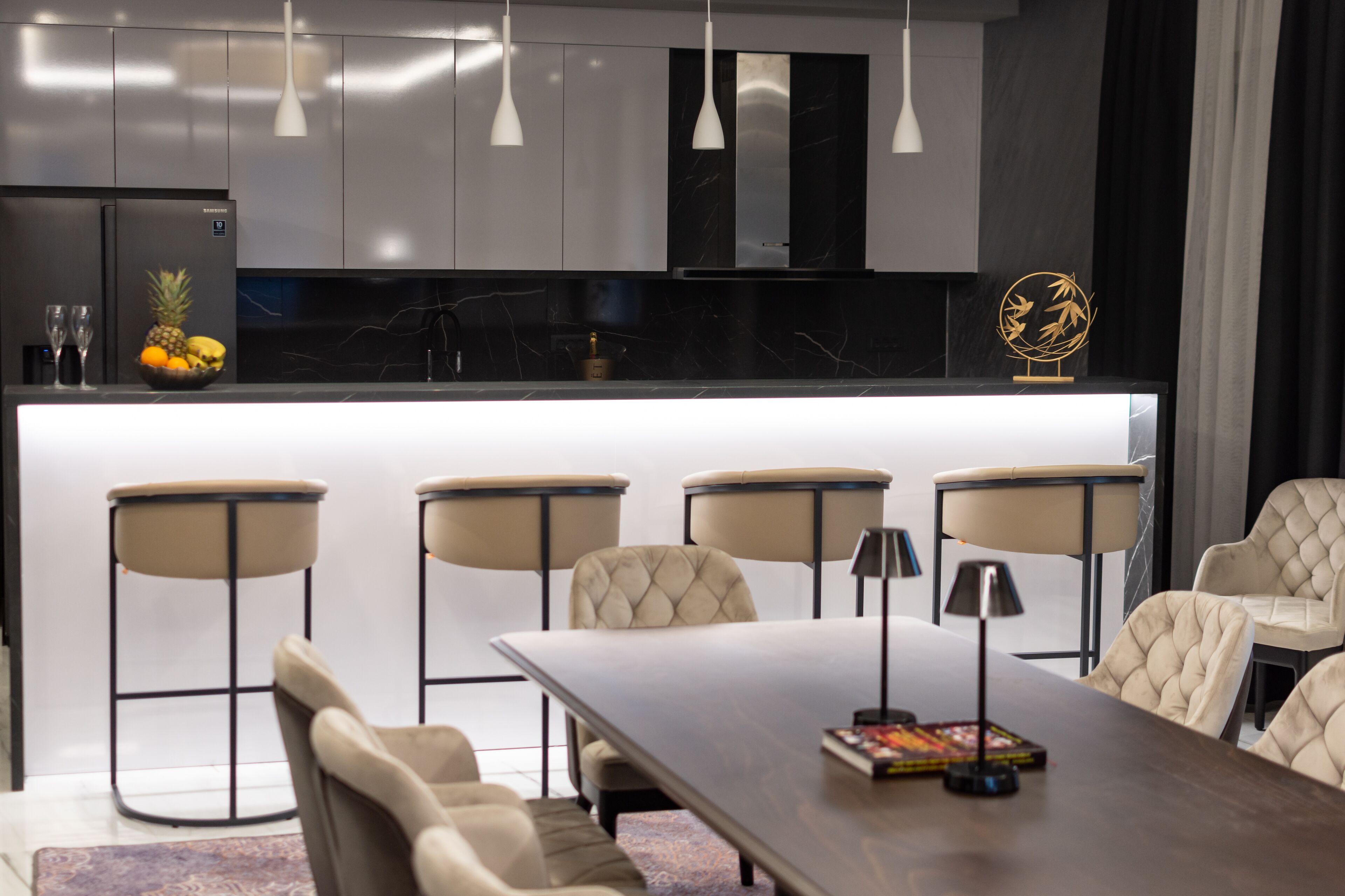 Una cocina moderna con una isla central, taburetes de bar y una mesa de comedor con sillas.