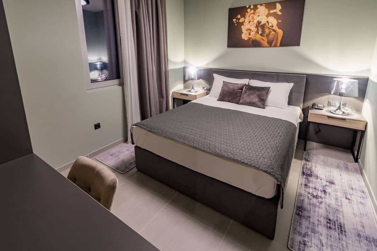A hotel room with a large bed, two bedside tables, a desk, and a chair.