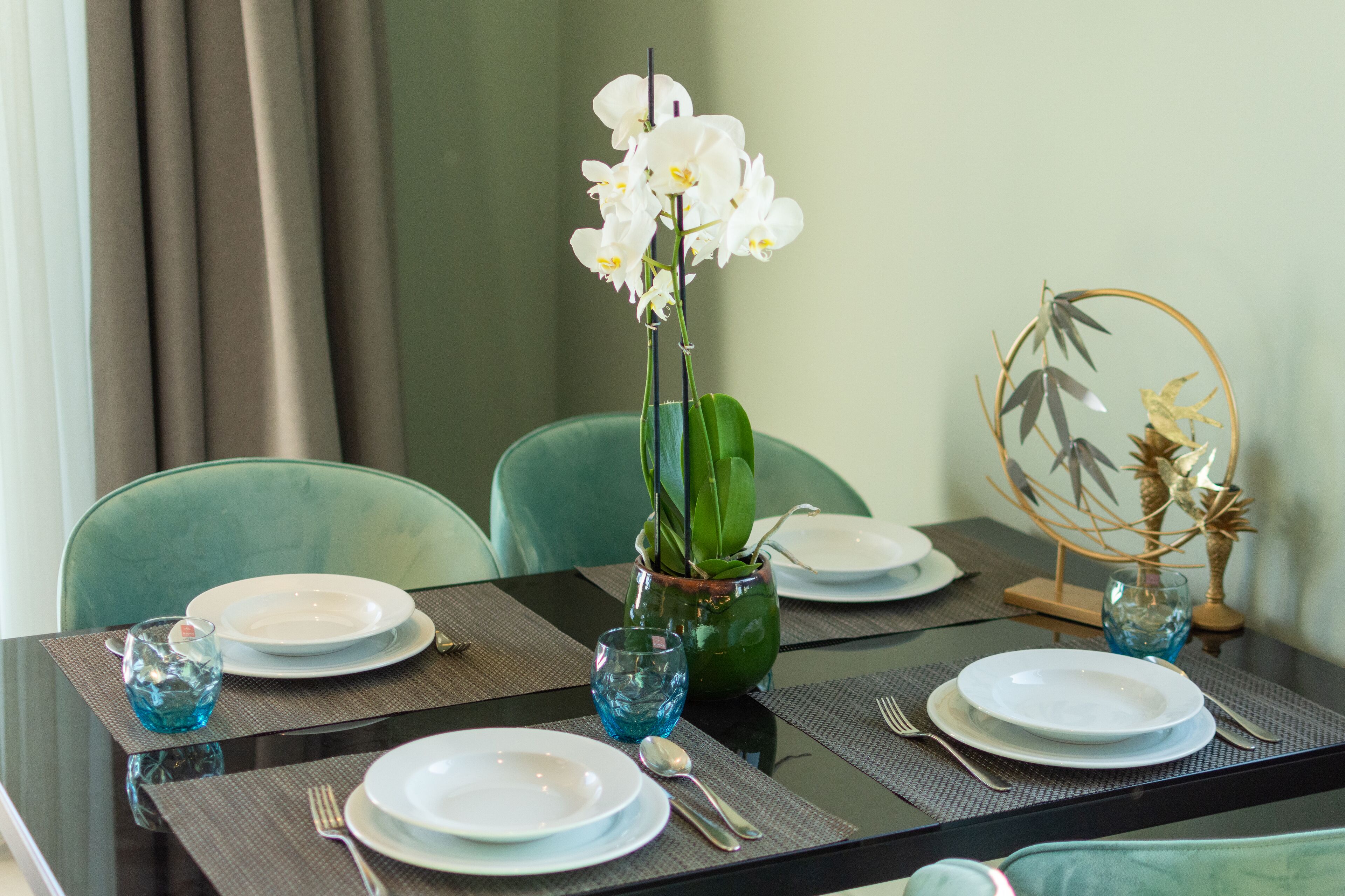 A dining table set with plates, cutlery, and a vase with white flowers.
