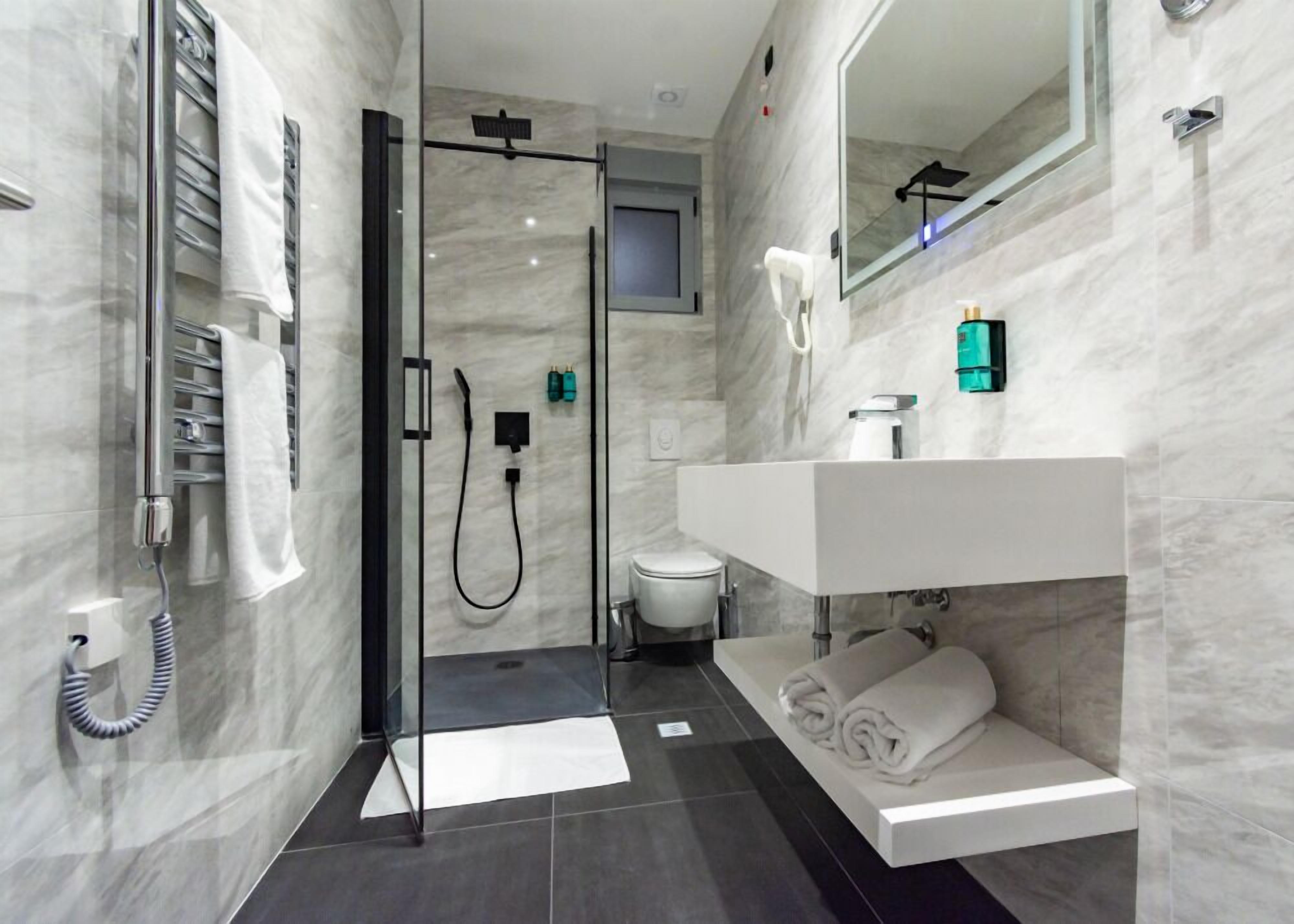 A modern bathroom with a glass-enclosed shower, a white sink, and a mirror.