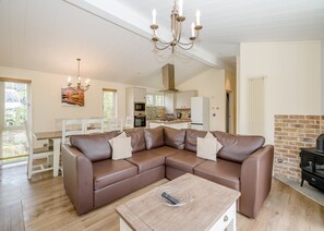 Ein modernes Wohnzimmer mit einer Eckcouch, einem Holztisch, einer Kronleuchter und einem Kamin.