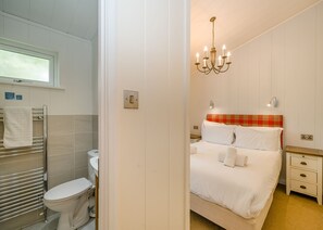 Ein Hotelzimmer mit Bett, Nachttisch, Toilettenartikel und einem Hängeleuchter. Ein Handtuchhalter ist ebenfalls vorhanden.