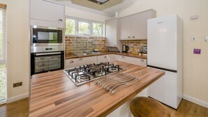 Een moderne keuken met een gasfornuis, oven en een inbouwmagnetron.