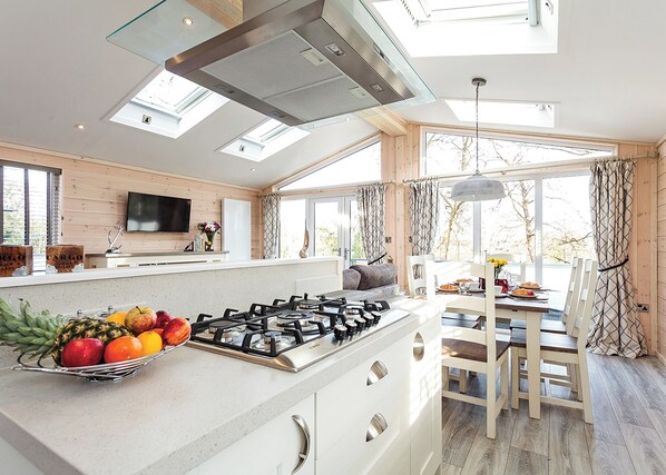 A modern kitchen with a gas stove, a fruit basket, and a dining area with a table and chairs. - 1 bedroom accommodation in Wootton Bridge, Nr Cowes (Wootton Bridge, Nr Cowes)