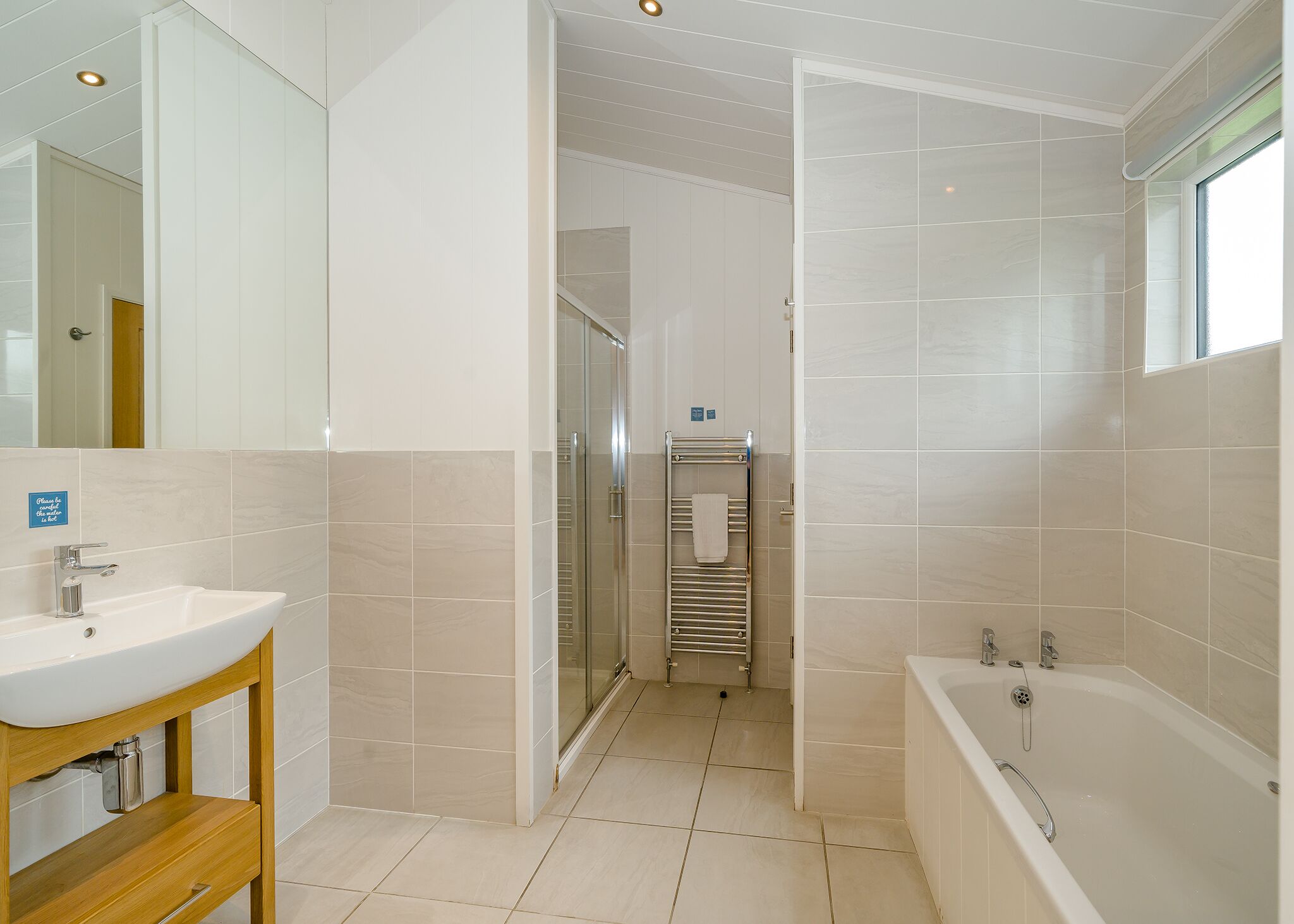 Un baño moderno con lavamanos, espejo, ducha y bañera.