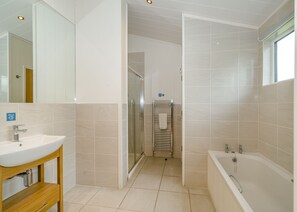 Une salle de bain moderne équipée d’un lavabo, d’un miroir, d’une douche et d’une baignoire.