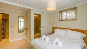 Hotelkamer met een bed, inloopkast, douche en raam met zonwering.