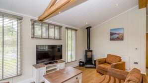 Een woonkamer met een televisie, houten bijzettafeltje, bank en een open haard.