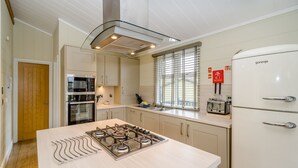 Een moderne keuken met een gasfornuis, roestvrijstalen apparatuur en een witte koelkast.