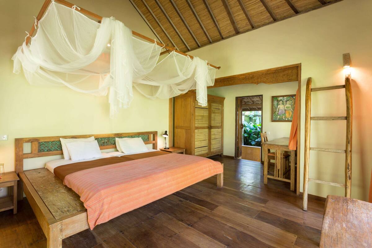 Ein Schlafzimmer mit einem hölzernen Bett, einem Baldachinbett, einem Holztisch und einer Leiter.