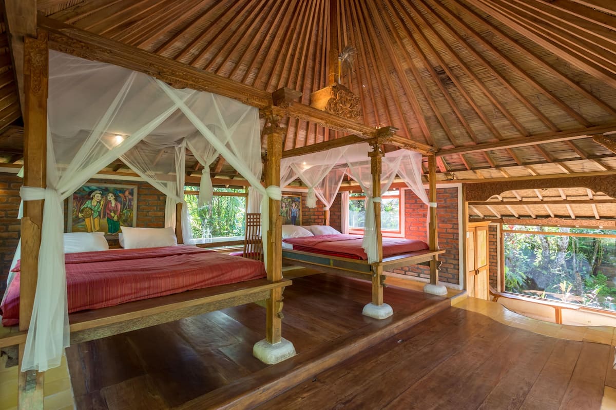 Ein Zimmer mit vier Betten, jedes mit Baldachin, Holzböden und einer Wandmalerei.