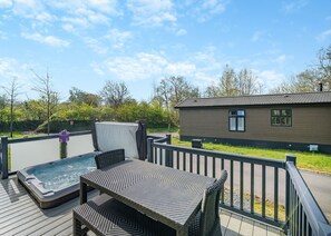 Une terrasse dotée d’un jacuzzi, de mobilier d’extérieur et d’un bâtiment avec une fenêtre.