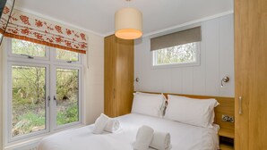A bedroom with a bed, two windows, a wooden wardrobe, and a ceiling light. - 1 bedroom accommodation in Bewaldeth, Keswick (Bewaldeth, Keswick)