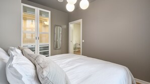 A bedroom with a large bed, a walk-in closet, and a mirror on the wall.