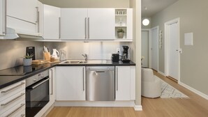 A modern kitchen with white cabinetry, stainless steel appliances, and a black countertop.