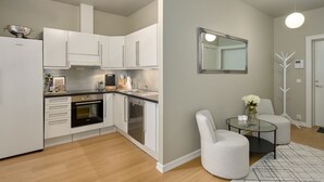 A modern kitchen with white cabinets, stainless steel appliances, and a dining area with a glass table and white chairs.