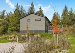 A modern, single-story building with a grey exterior and a small deck area. - Elkstone Premier Lodge (Ashbourne)