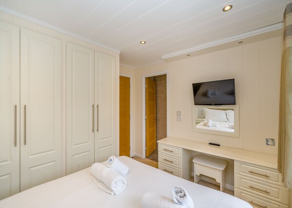 A hotel room with a bed, a desk, a television, and a wardrobe.