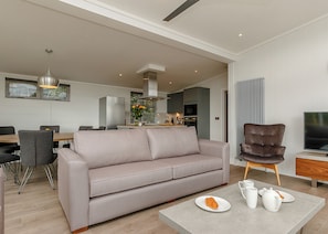 Un salon moderne avec un canapé, une table basse sur laquelle se trouve un croissant et un téléviseur.