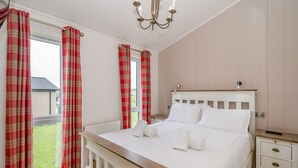 A bedroom with a bed, a nightstand, a bedside table, a window with curtains, and a chandelier. - 1 bedroom accommodation in Bewaldeth, Keswick (Bewaldeth, Keswick)