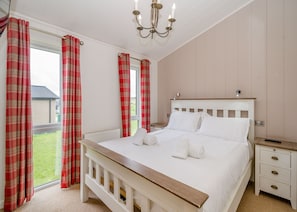 A bedroom with a bed, a nightstand, a bedside table, a window with curtains, and a chandelier. - 3 bedroom accommodation in Bewaldeth, Keswick (Bewaldeth, Keswick)