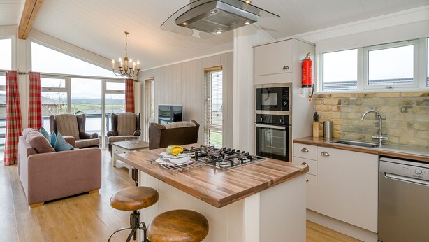 A modern kitchen with a central island, bar stools, a built-in oven, and a dishwasher. - 1 bedroom accommodation in Bewaldeth, Keswick (Bewaldeth, Keswick)