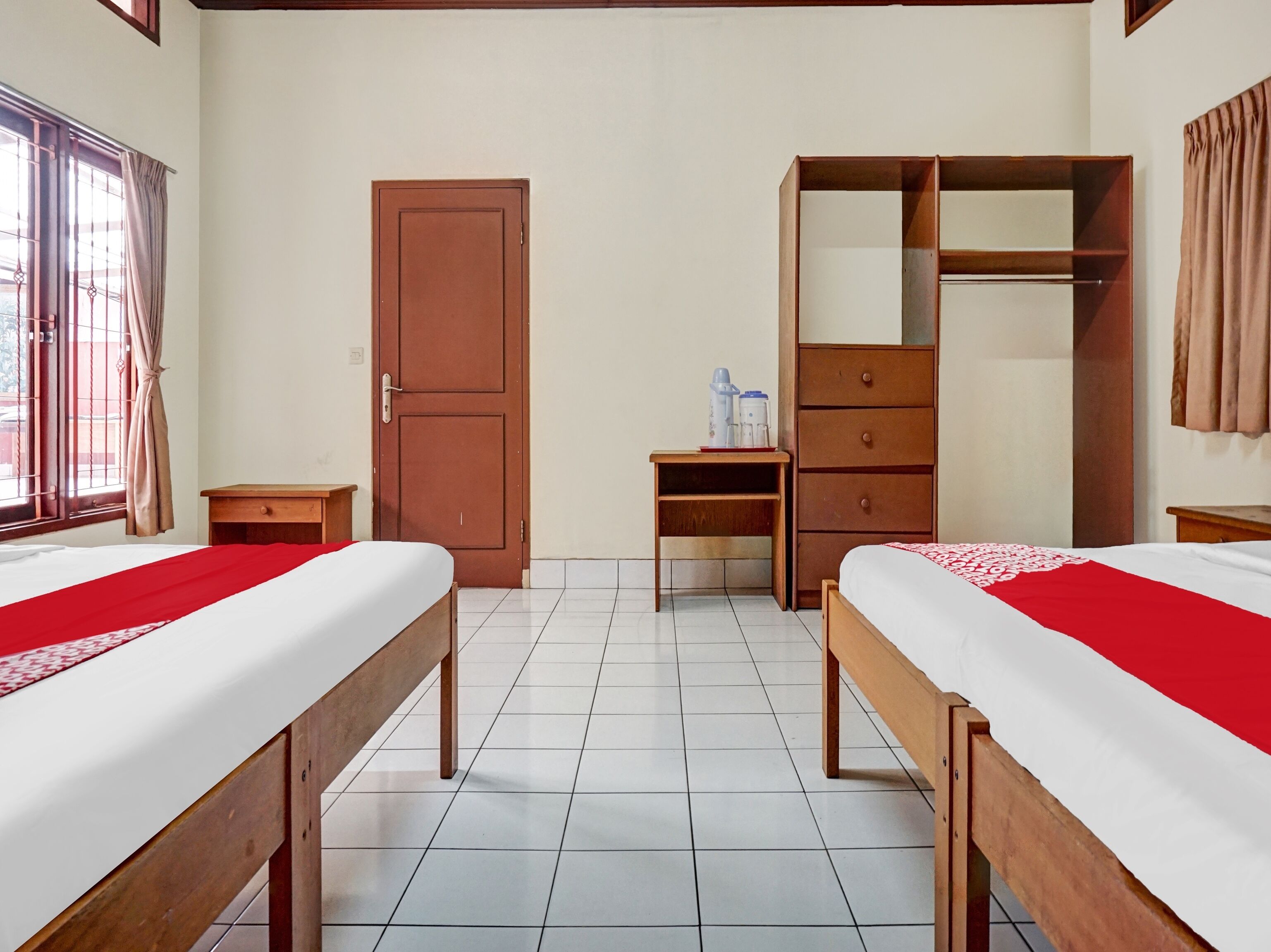 Habitación de hotel con dos camas, un armario, un escritorio y una ventana con cortinas.