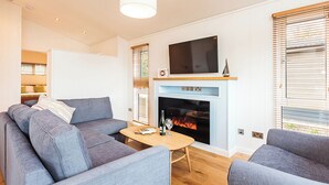Un salon moderne avec un canapé, une table basse, une cheminée et un téléviseur fixé au-dessus.