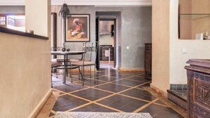 Un coin repas avec une table et des chaises, un tableau accroché au mur et un sol carrelé.