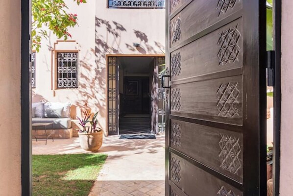 A doorway leading to a courtyard with a sofa and a potted plant. - Charming villa, located 10 minutes from the ocean (Agadir)