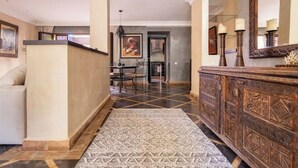 Un couloir avec un tapis à motifs, un meuble en bois et un coin repas comprenant des chaises et une table.