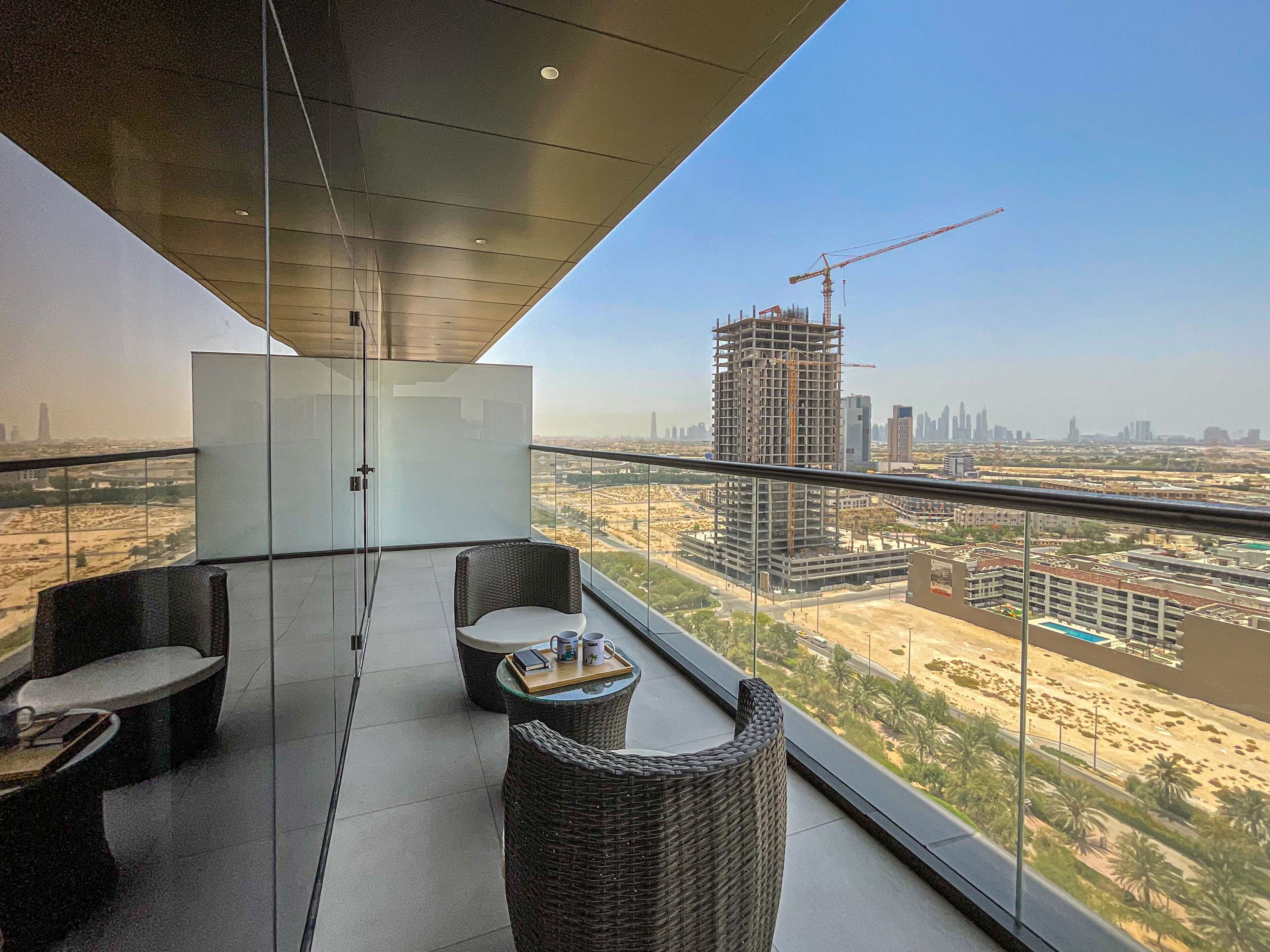 A balcony with wicker furniture and a view of a construction site.