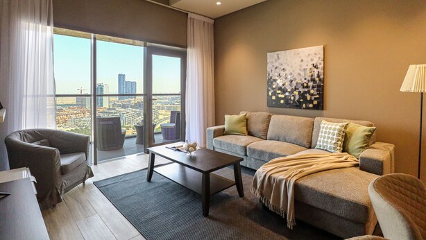 Una sala de estar moderna con sofá, sillón y una mesita de centro. Un ventanal ofrece vistas a la ciudad.