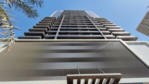 Un moderno edificio de gran altura con una fachada geométrica distintiva, ventanas amplias y una entrada visible con marquesina.