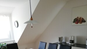 Een moderne keuken met een eethoek. Er staat een witte tafel met zwarte stoelen, een koffieapparaat en een waterkoker.
