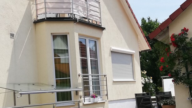 Een gebouw met een balkon, een raam met uitzicht en een geplaveid binnenterrein.