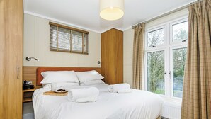 A bedroom with a bed, wooden wardrobe, bedside table, and a window with curtains. - 4 bedroom accommodation in Bewaldeth, Keswick (Bewaldeth, Keswick)