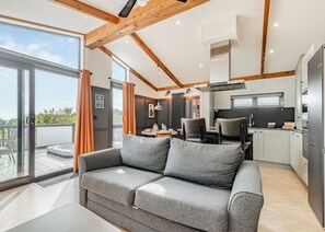 Un interior moderno con un sofá gris, una zona de comedor y una cocina.