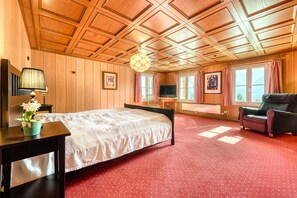 A room with a wooden ceiling, a bed, a TV, and a sofa. - Berghaus Tschengla (Buerserberg)