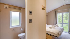 Une chambre d’hôtel moderne équipée de toilettes, d’une fenêtre, d’un lit et d’un luminaire fixé au mur.