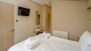 Une chambre d’hôtel équipée d’un lit, d’une télévision, d’un miroir, d’une salle de bain et d’un radiateur.