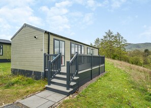 Une maison mobile dotée d’un porche à l’avant, de quelques marches et offrant une vue sur le paysage environnant.