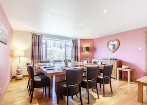 Un coin repas avec une grande table, des chaises, une lampe et un miroir en forme de cœur accroché au mur.
