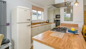 A modern kitchen with a central island, stainless steel appliances, and a view of the outdoors. - 2 bedroom accommodation in Bewaldeth, Keswick (Bewaldeth, Keswick)