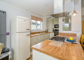 Eine moderne Küche mit Kochinsel, Edelstahlgeräten und Blick ins Freie.