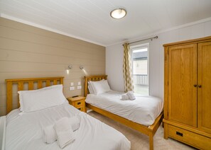 Ein Schlafzimmer mit zwei Betten, einem Kleiderschrank, einem Fenster mit Vorhängen und einer Deckenleuchte.