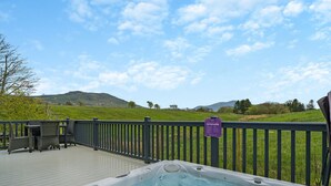 A hot tub on a deck with a view of a grassy field and hills. - 2 bedroom accommodation in Bewaldeth, Keswick (Bewaldeth, Keswick)