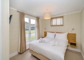A bedroom with a bed, a window with curtains, a bedside table, and a hanging light fixture.