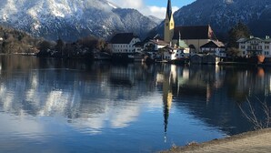 A lakeside town with a church, houses, and snow-capped mountains in the background. - Small apartment for a maximum of 2 people in a unique location directly on the lake (Rottach-Egern)